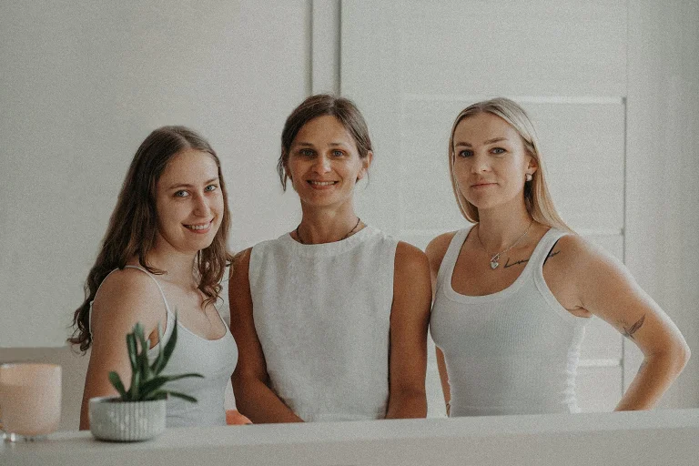 Trzy uśmiechnięte instruktorki Holica Studio w białych strojach